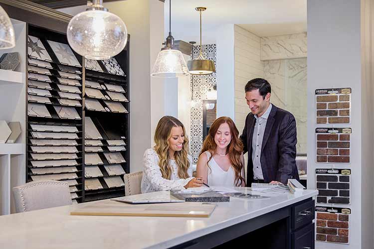 A Design Center Consultant shows two customers cabinet samples