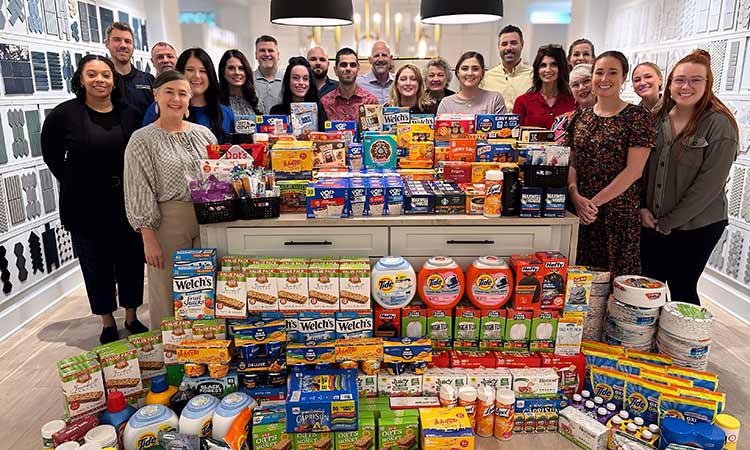 David Weekley Team Members in Austin, TX standing behind a large collection of food and household products for donation