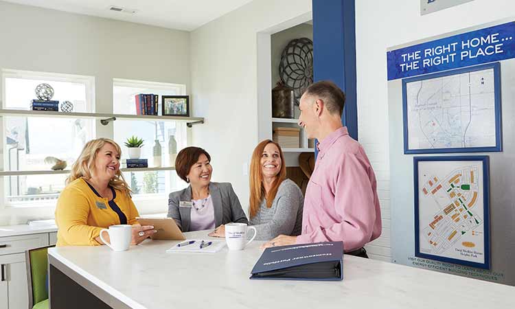 David Weekley Homes Team Members sitting with a Real Estate Agent in a model home sales center