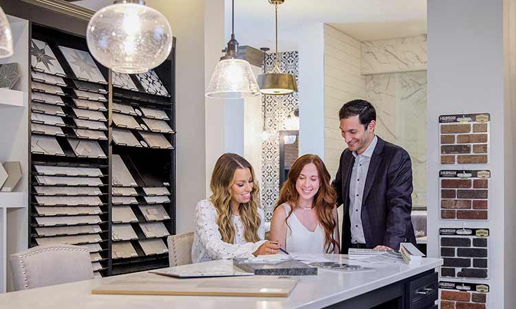 a man and woman sit at a David Weekley Homes Design Center with a Design Consultant and look at tile samples