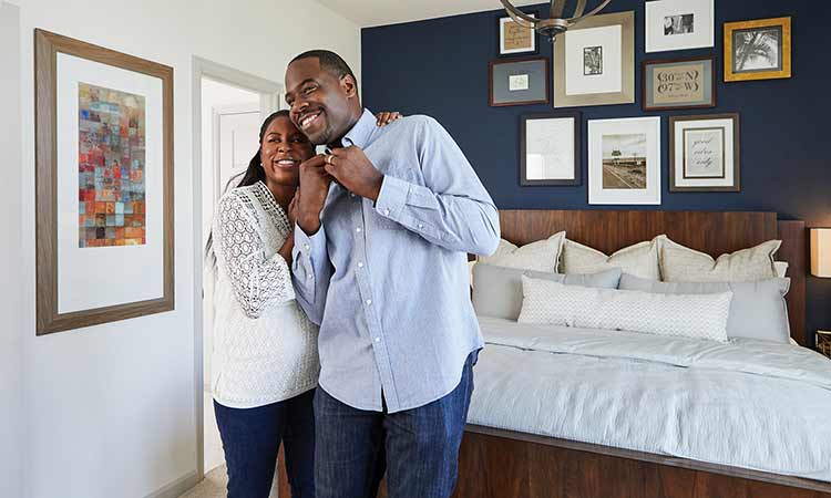 a man and a woman stand in a bedroom