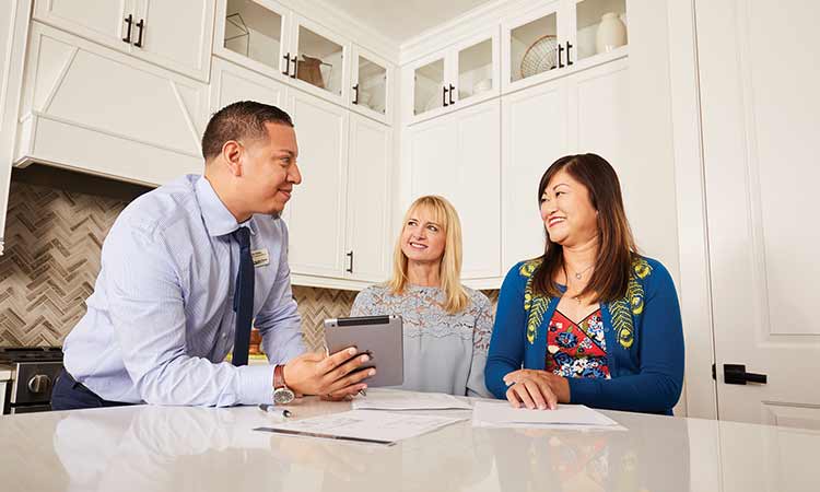 David Weekley Homes Team Member standing at kitchen counter with two customers