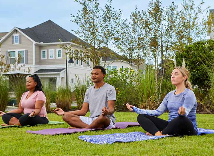 Three people outside, sitting on yoga mats