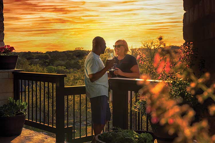 a man and woman standing on a deck during sunset