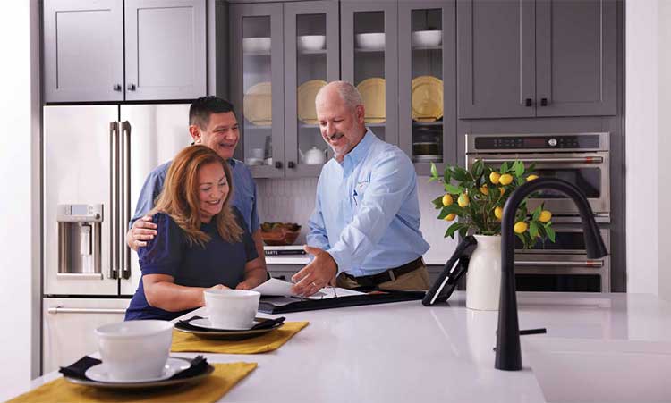 A David Weekley Homes Wwarranty Representative talks with homeowners in a kitchen