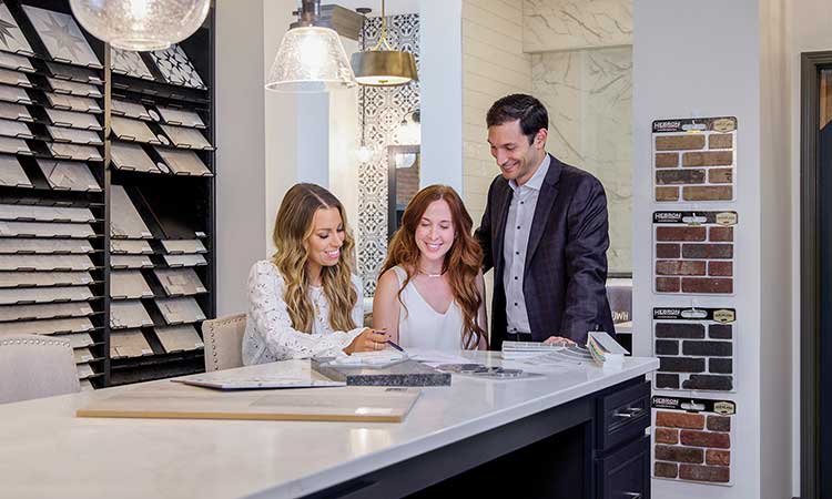 A David Weekley Homes Team Member shows a man and a woman kitchen options at the Design Center