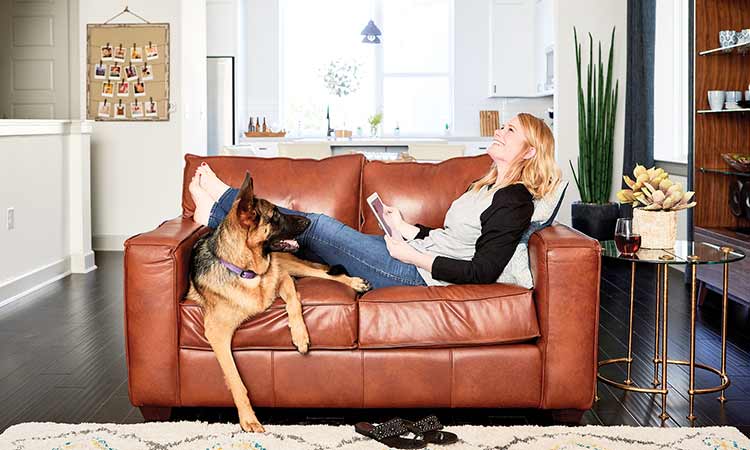 A David Weekley Homeowner sits on a couch with her dog