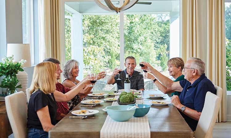 six people sitting at a dining table while holding up wine glasses
