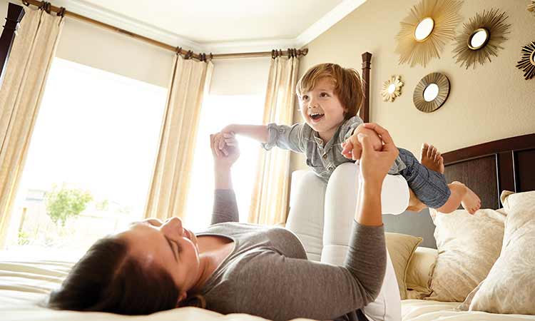a woman lays in bed holding a child