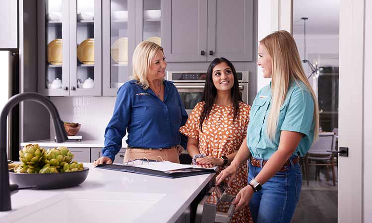 A David Weekley Homes Warranty Service Manager and Personal Sales Consultant talking with a Homeowner in a kitchen