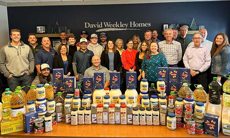 David Weekley Homes Team Members standing behind a table of food donations at a past Thanksgiving Drive in Indianapolis, IN