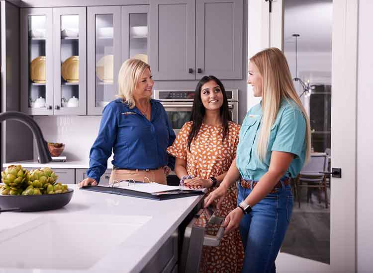 Two David Weekley Homes Team Members talk with a customer in a kitchen