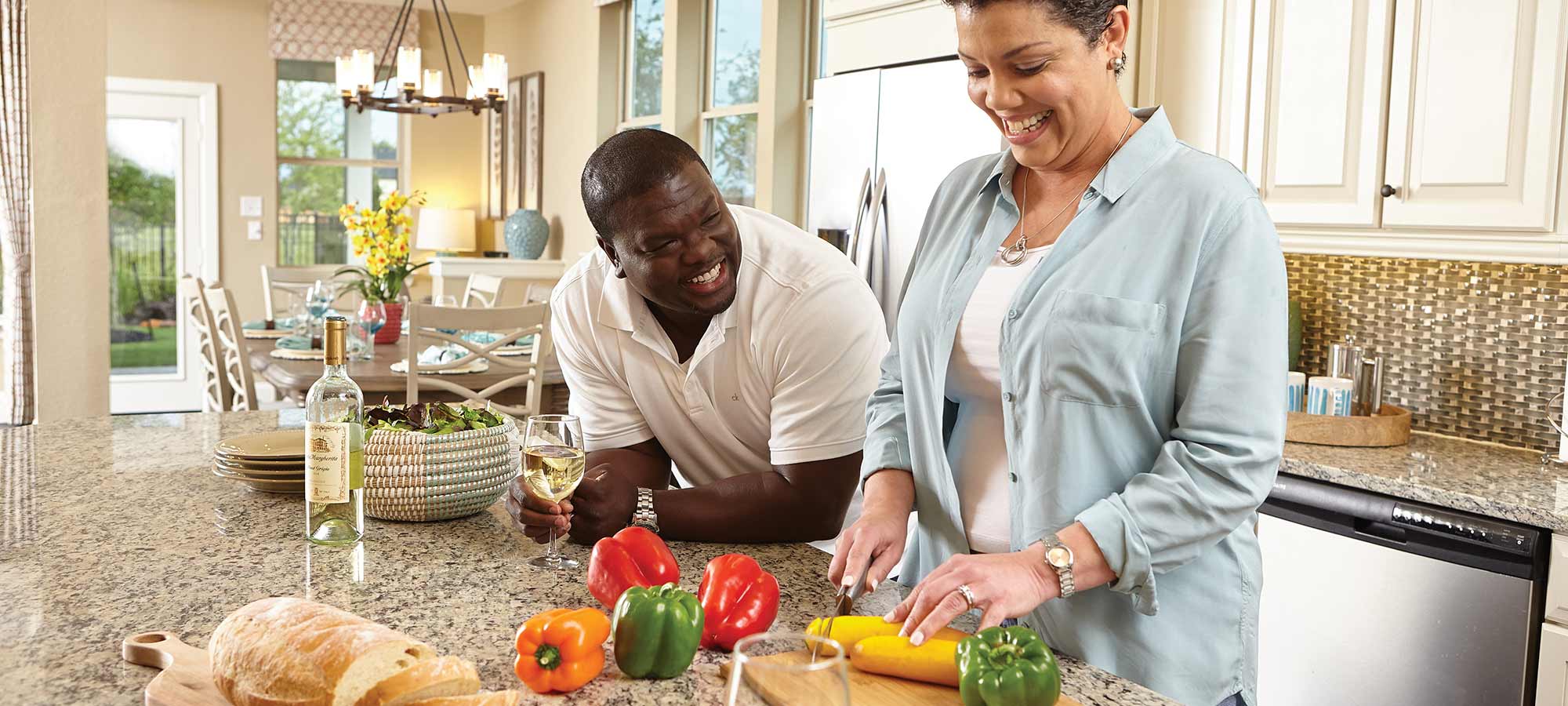 a man and woman stand at a kitchen counter, the woman is chopping vegetables