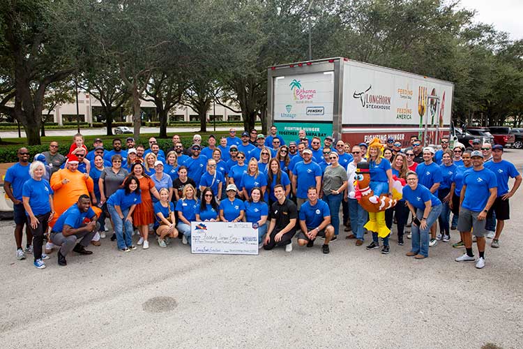 David Weekley Homes Team Members posing with a large truck and a large donation check at a past Thanksgiving Drive in Tampa, FL