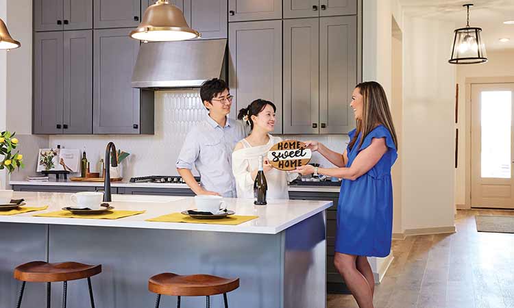 David Weekley Homes Team Member standing at kitchen counter with two customers
