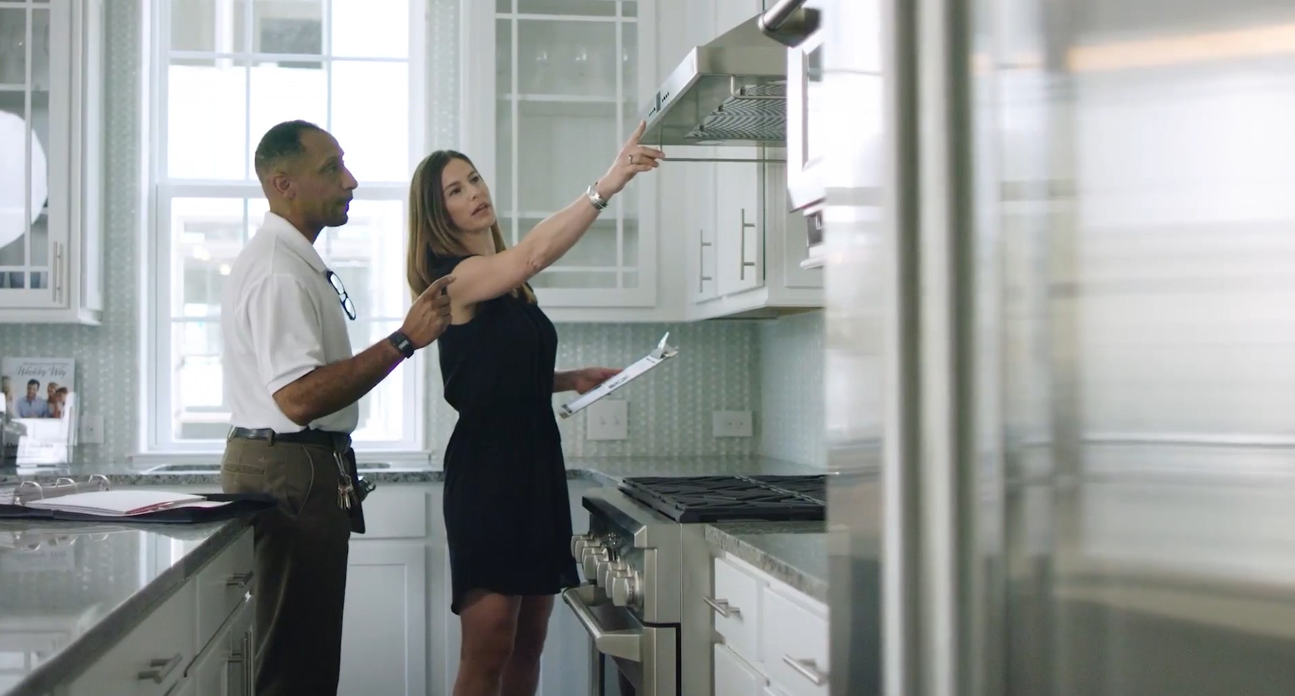a man and woman looking at a stove in a kitchen