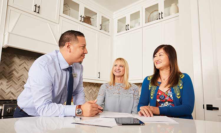 David Weekley Homes Team Member standing at kitchen counter with two customers