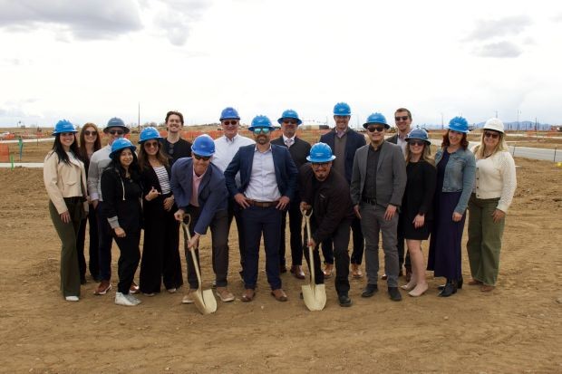 several people wearing hard hats and holding shovels