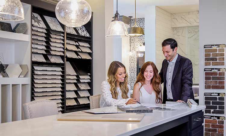 A David Weekley Homes Design Consultant shows a man and a woman kitchen samples