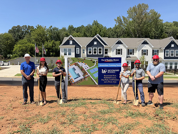 a group of people standing while hold shovels at a groundbreaking ceremony