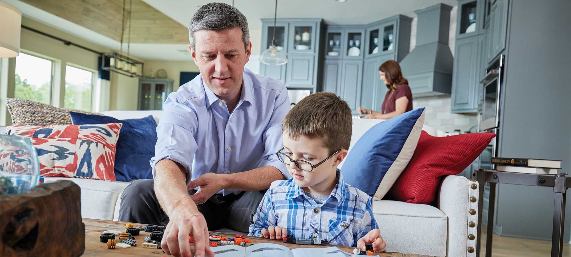 A man sitting with on a couch with a child, looking at a book