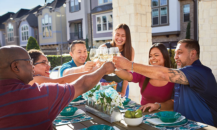 a group of David Weekley Homeowners sit at a table outside holding glasses