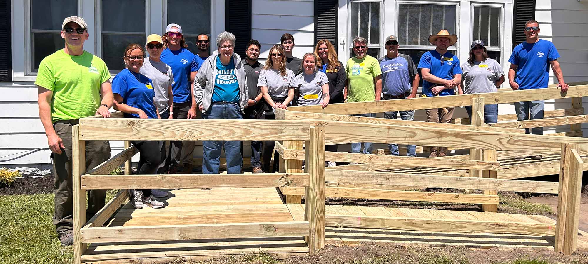a group of David Weekley Homes Team Members stand on a wheelchair ramp that was built during a CARE event