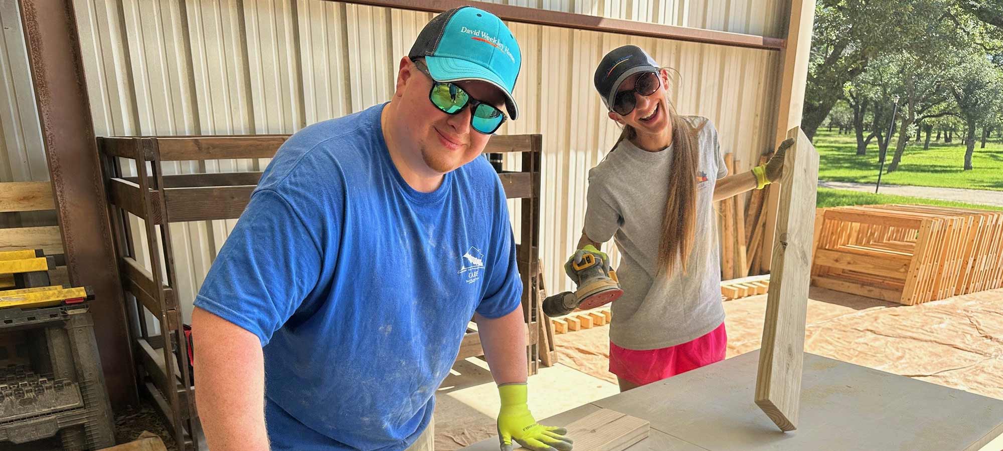 a man and a woman are smiling as they sand wood