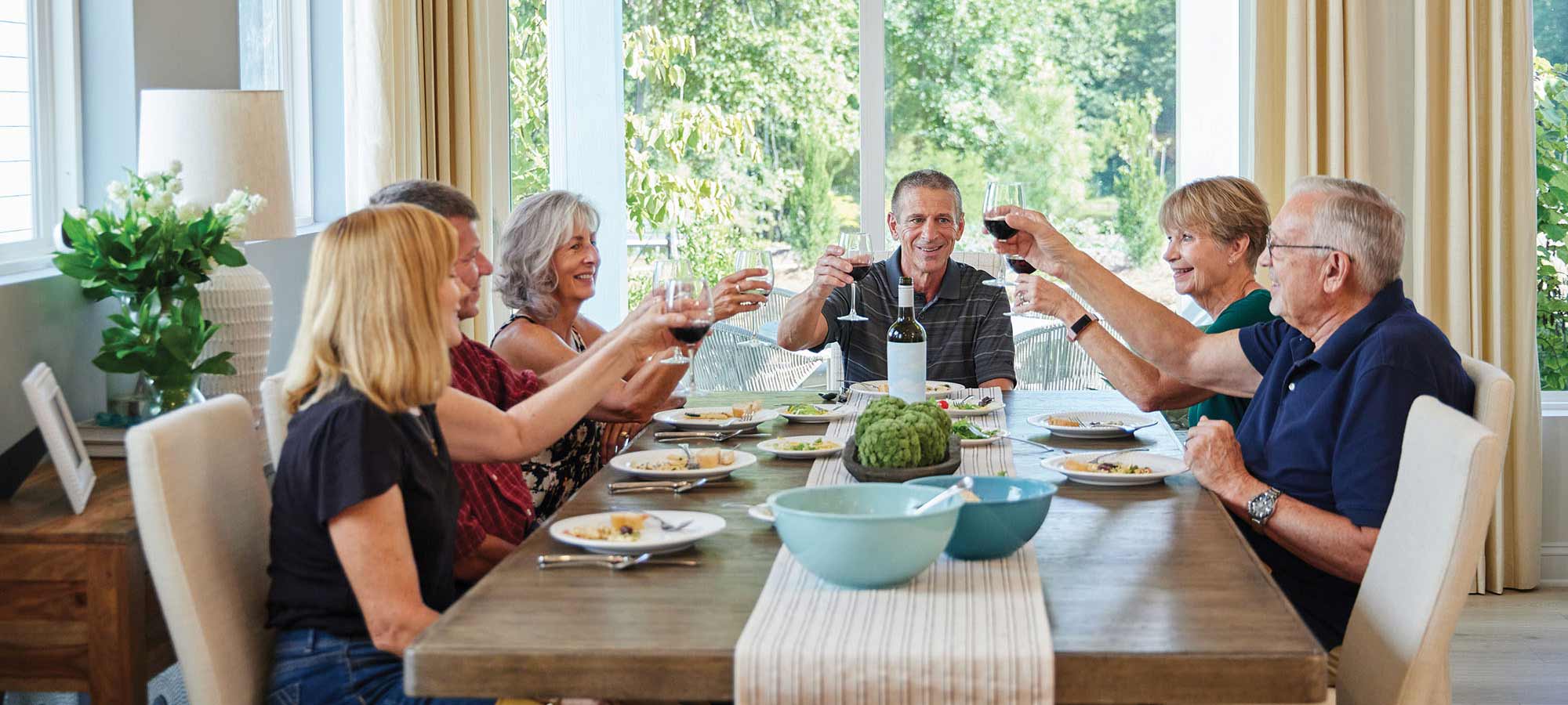 Encore by David Weekley Homes Homeowners sitting a dining table raising their glasses of wine in a toast