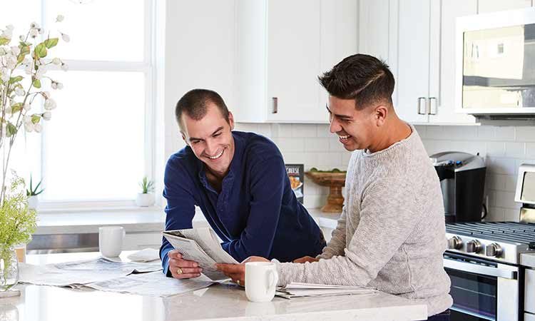 Two David Weekley Homeowners stand at a kitchen counter looking at a newspaper