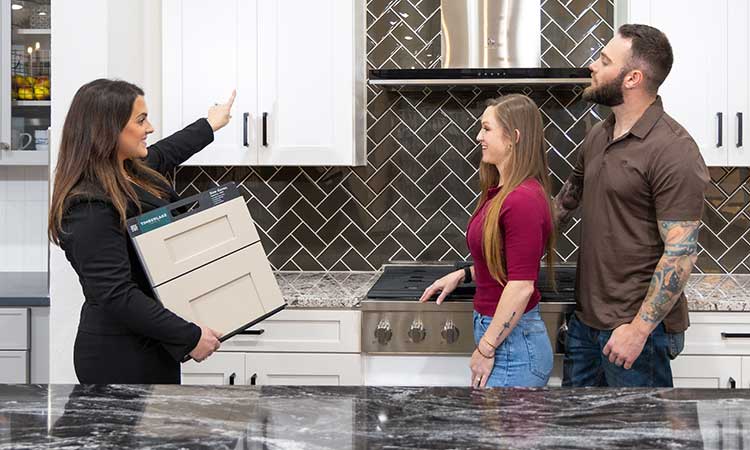 A David Weekley Homes Design Consultant shows cabinet samples to cusomters