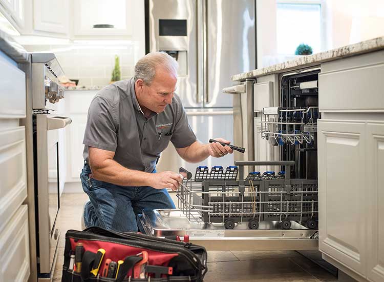 A David Weekley Homes Warranty Represenative inspects a dishwasher